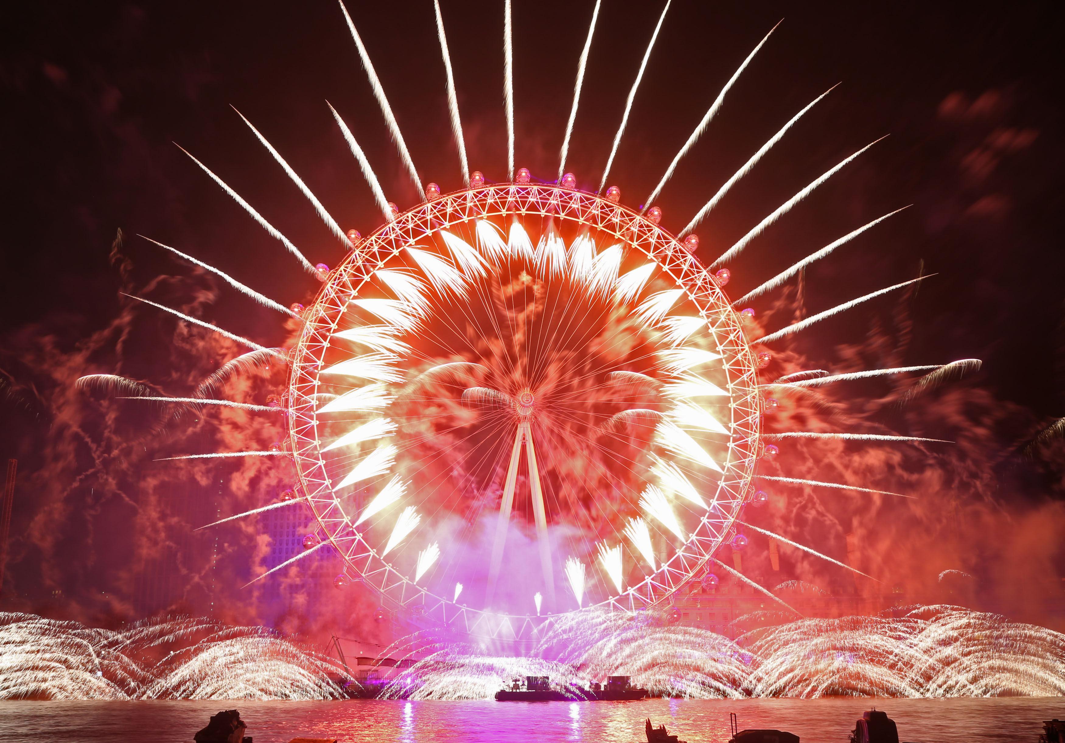 Более 100 000 гуляк собрались в Лондоне, где Око было освещено, как гигантское Екатерининское Колесо, и над Темзой взорвалось 12 000 фейерверков
